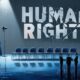 Ilustrasi simbolis panggung debat kosong dengan tulisan “HUMAN RIGHTS” retak dan aktivis bayangan di bawah hujan.