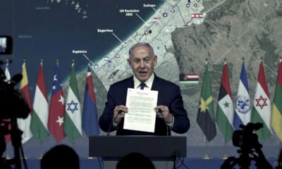 Netanyahu memegang dokumen Resolusi 2803 dalam konferensi pers dengan peta Gaza di layar belakang